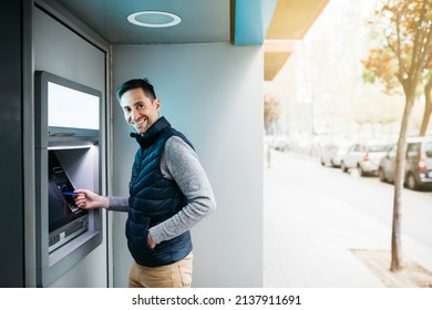 Man introducing a blue credit card to an ATM street machine