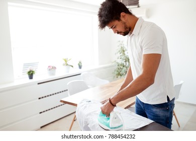 Man Ironing Shirt On Ironing Board