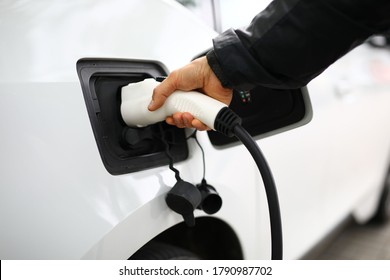 A man in a jacket inserted a fuel hose into a white car. Service at a gas station - Shutterstock ID 1790987702