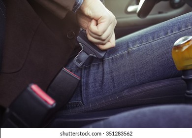 Man in a jacket and jeans buttons in the car seat belt, ready for the trip by car. Safety on the road, the driver's life.