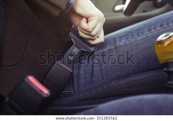 Man
in a jacket and jeans buttons in the car seat belt, ready for the
trip by car. Safety on the road, the driver's
life.