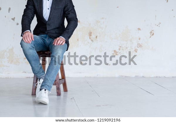 man in jacket\
and jeans sitting on a chair. confident business trainer or\
entrepreneur. smart casual dress\
code.