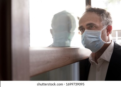 Man In Jacket With Protective Face Mask, Is Leaving His House Worriedly Because Of The Coronavirus