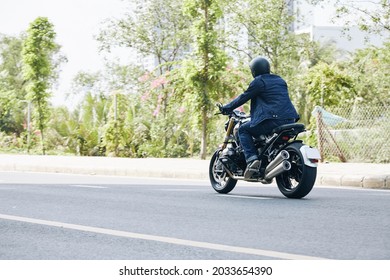 Man In Jeans And Denim Jacket Riding On Motorcycle On Highway, View From The Back