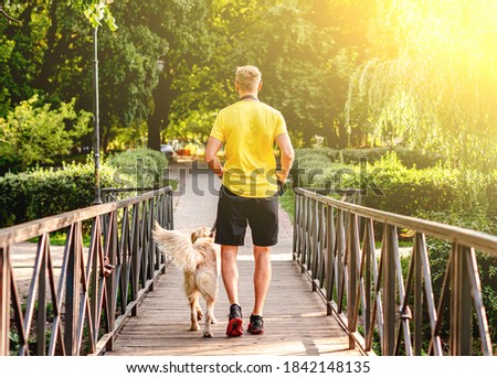 Man jogging across bridge with dog