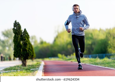 Man jogging in the morning out on the race track - Shutterstock ID 619624334