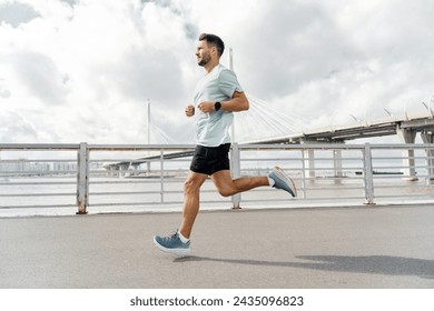 Man jogging on a sunny day with a bridge in the background, focused on his fitness goals.

 - Powered by Shutterstock