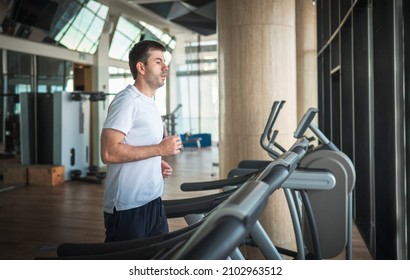 Man Jogging On A Treadmill During A Cardio Running Warmup Exercise In The Gym For Staying Fit And In Shape With Fitness Lifestyle