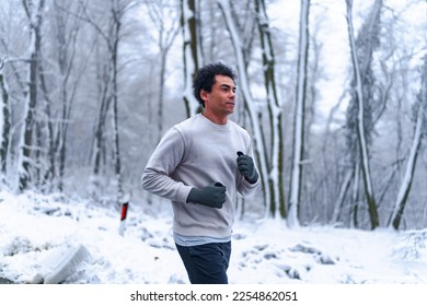 Man jogging in winter, surrounded by nature covered in snow. - Shutterstock ID 2254862051