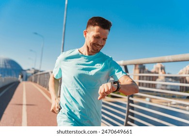 A man jogs on a pathway, checking his watch while running, with a bright blue sky in the background.