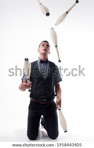 A man juggler on a white background juggles with clubs. Juggler's day 