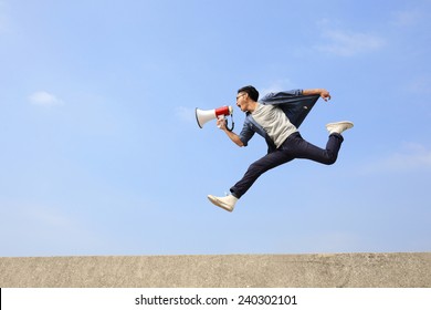 man jump and shout by megaphone with blue sky background, asian