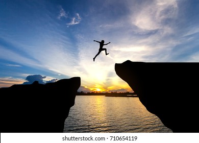 Man jump through the gap between hill.man jumping over cliff - Shutterstock ID 710654119