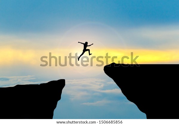 Man jump through the gap between hill.man jumping\
over cliff