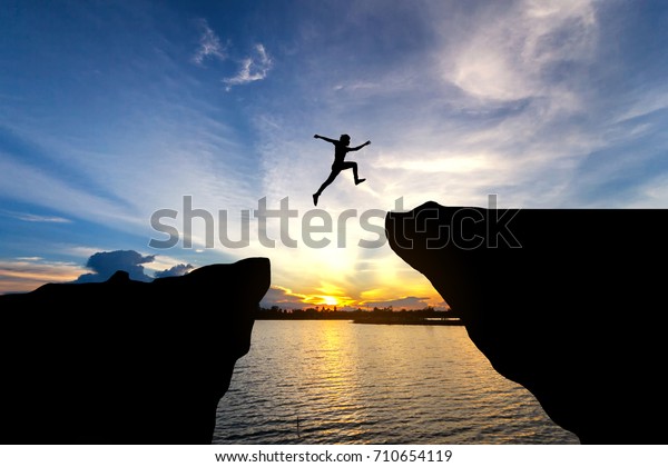 Man jump through the gap between hill.man jumping\
over cliff