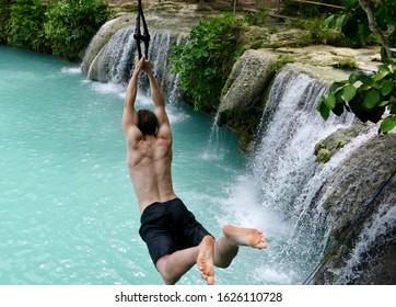 Man jumping from cliff into natural pool before waterfall , in air, cambugahay falls, Siquijor, Philippines - Powered by Shutterstock