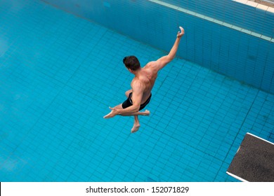 Man Jumping From Diving Board At Public Swimming Pool