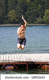 man jumping into lake plugging his nose
