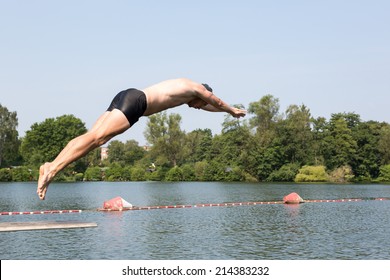 Man Jumping Off Diving Board At A Public Swimming Pool