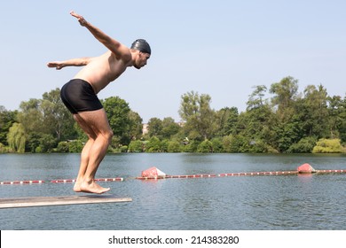 Man Jumping Off Diving Board At A Public Swimming Pool