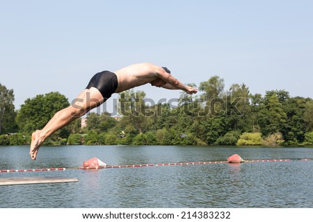 Man jumping off diving board at a public swimming pool
