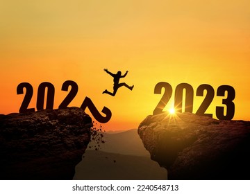 Man jumping on cliff 2023 over the precipice with stones at amazing sunset. New Year's concept. 2022 falls into the abyss. Welcome 2023. People enters the year 2023, creative idea. - Shutterstock ID 2240548713