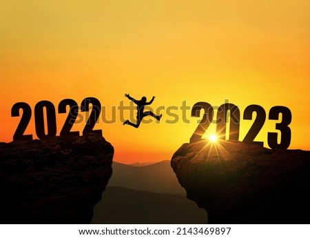 Man jumping on cliff 2023 over the precipice at amazing sunset. New Year's concept. Symbol of starting and welcome happy new year 2023. People enters the year 2023, creative idea