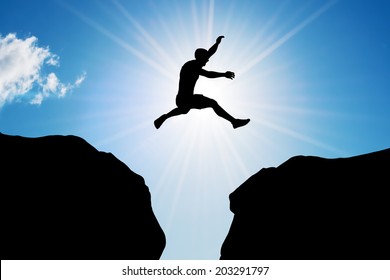 Man jumping over precipice between two rocky mountains at sun light. Freedom, risk, challenge, success. - Powered by Shutterstock