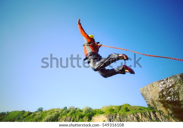 A man jumps from a\
cliff into the abyss.