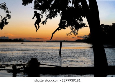 Man jumps into the Amazon river at sunset - Shutterstock ID 2279939181