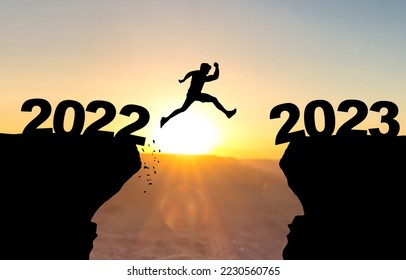 Man jumps over abyss with sunset in background and inscription 2022 and 2023 - Shutterstock ID 2230560765