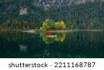 Man kayaking on lake in autumn. Active tourism. Small islands on the lake with fall colours and beautiful reflections
