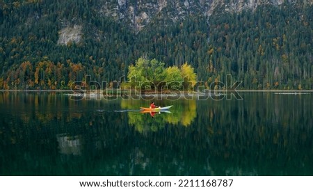 Man kayaking on lake in autumn. Active tourism. Small islands on the lake with fall colours and beautiful reflections

