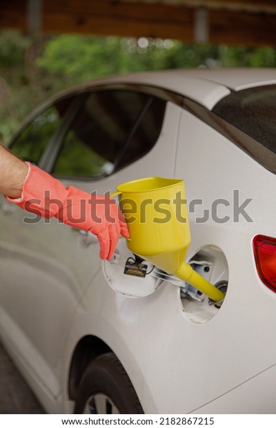 The man keeps a can for\
pouring gasoline from the canister into the car. Yellow watering\
can in the fuel holes. Gasoline collapse. Alternative fuelling\
method