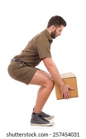 Man in khaki uniform picking up a carton box, side view. Full length studio shot isolated on white.
