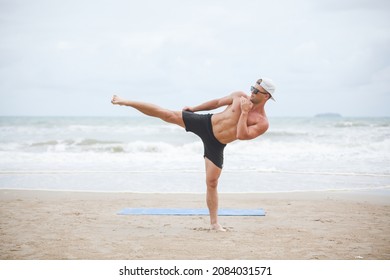 man kicks a high kick on the sandy sea, man train boxing fist fight on the beach - Powered by Shutterstock