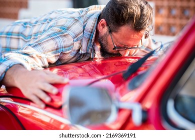 Man kiss his new car. Automobile lovers and owner hugging his vehicle. Concept of dreams and buying. Satisfied guy with closed eyes embracing  the automobile. Dreaming man lying on car kissing it
