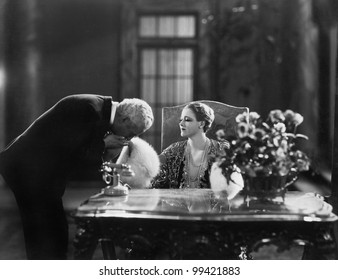 Man Kissing Hand Of Woman Sitting At Desk