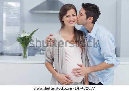 Man kissing his pregnant wife and touching his belly