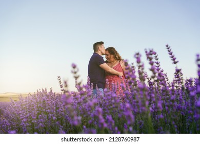 A Man Kissing A Plus Size Woman On The Forehead In A Lavender Field At Sunset. Happy Couple Concept.