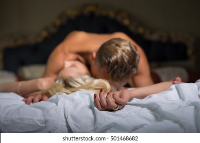 Man kissing woman's neck while she is lying on her back in bed