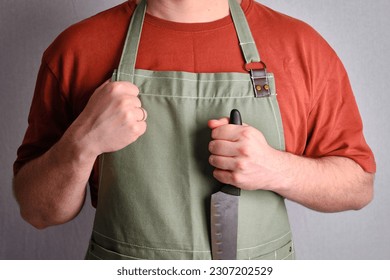 A man in a kitchen apron. Chef work in the cuisine. Cook in uniform, protection apparel. Job in food service. Professional culinary. Green fabric apron, casual stylish clothing. Handsome baker posing