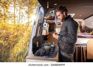Man in the kitchen area of his camper van in autumn