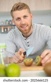 Man In Kitchen Cutting Sweet Kiwi Fruit With Knife