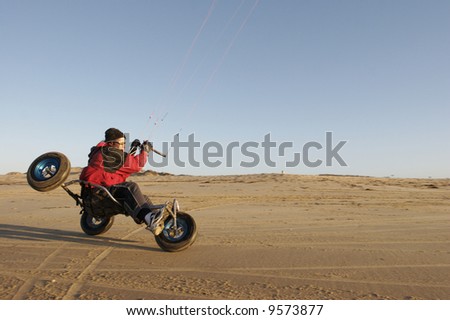 A man kite buggying at the beach at sunset