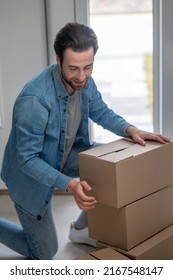 Man Kneeling Down Stacking Boxes Indoors