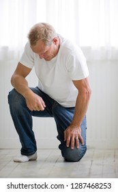 Man Kneeling On Floor And Looking Down