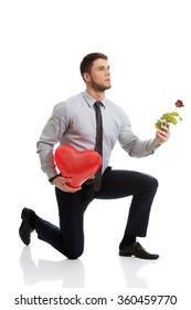 Man kneeling with red rose and heart balloon.