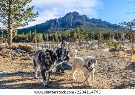 Man kneeling with Two Dogs in front of a mountain in Estes Park, CO, USA. Imagine de stoc © 