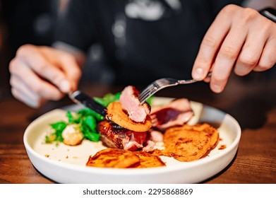 man with a knife and fork cuts grilled duck meat